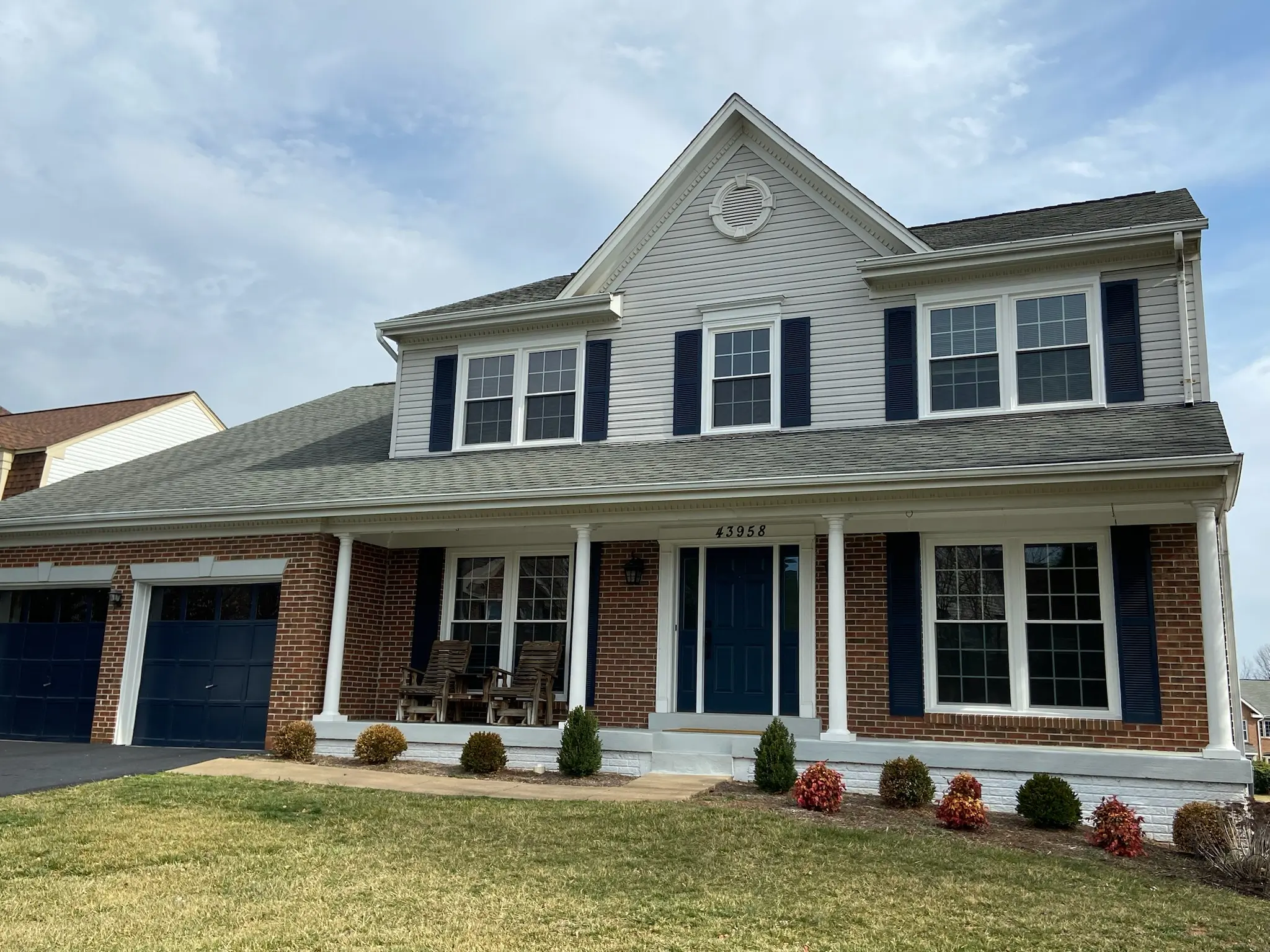 White vinyl siding colonial with brick porch in Sterling