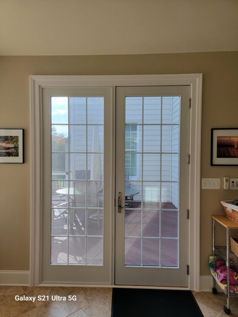 Interior view of double french patio doors with grid pattern, opening onto a back deck.