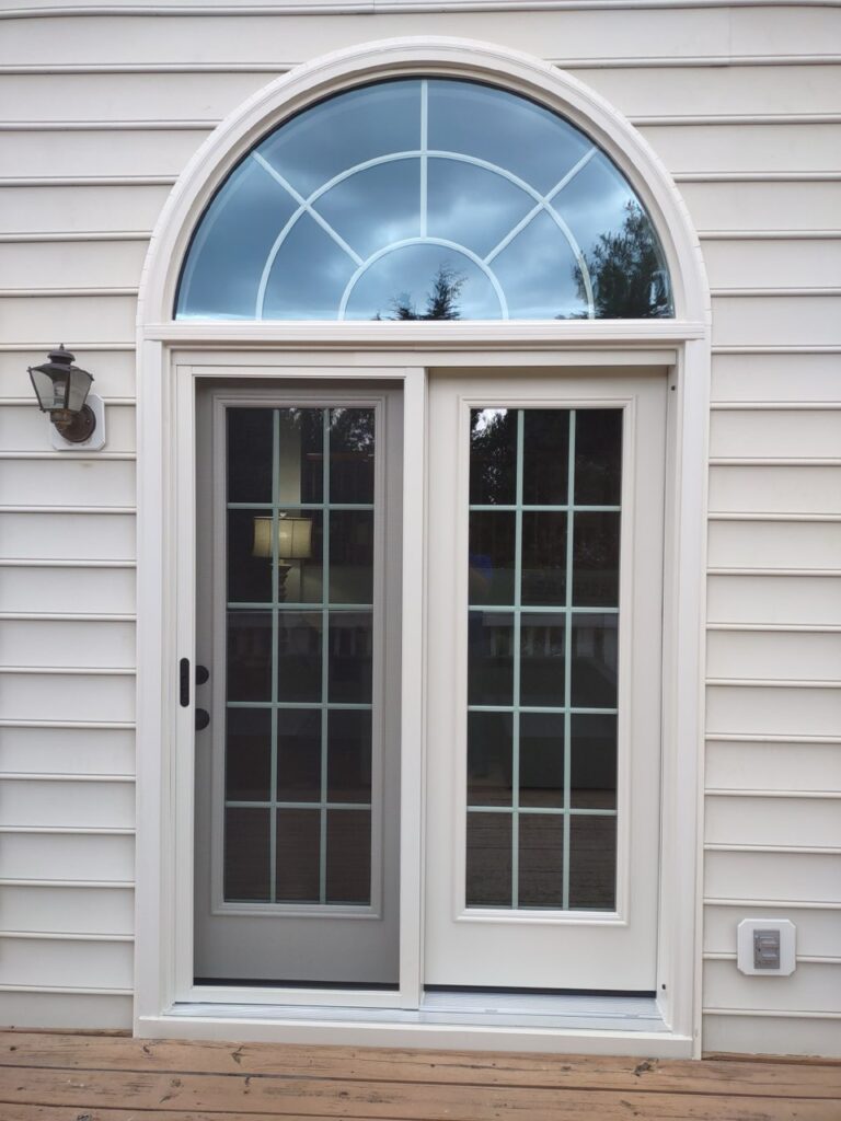 Two-panel sliding patio door with a half-round palladian transom window above, set into white lap siding.