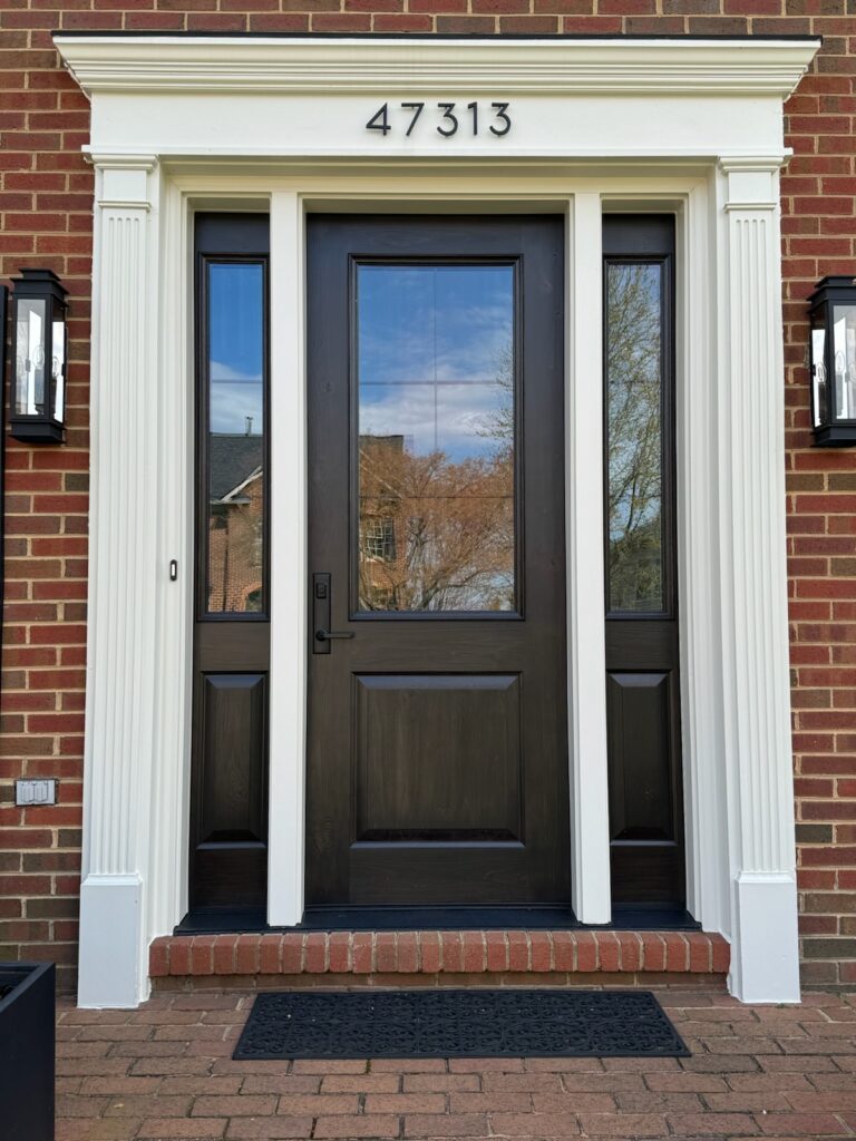 Dark-stained wood front entry door with glass top and pilaster-trimmed brick portico, house number 47313.