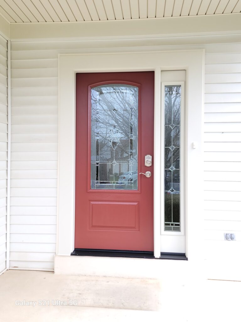 Red three-quarter-lite craftsman front entry door with decorative leaded-glass sidelight on white siding.