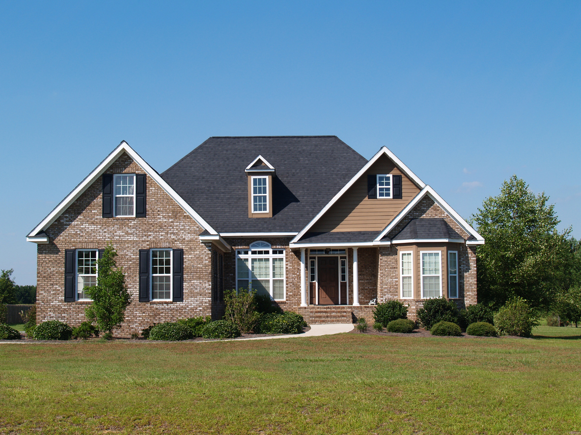Brick two-story colonial with black shutters on a wide lawn