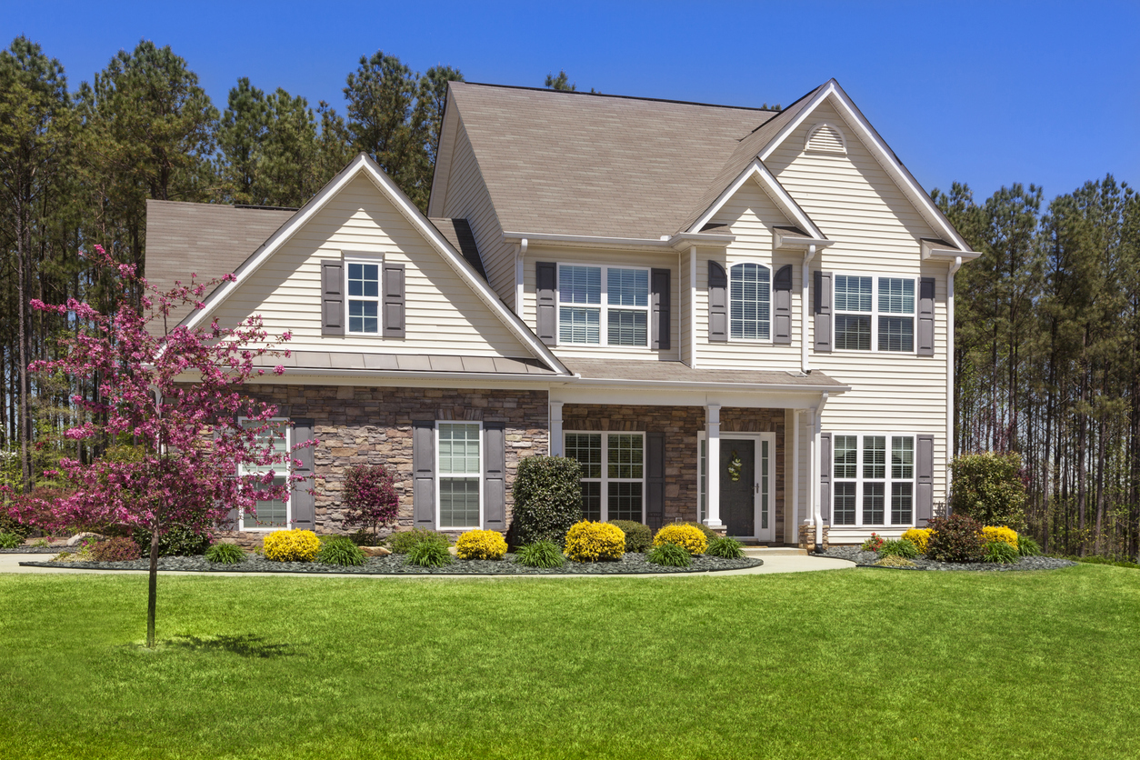 Two-story family home with stone accents backed by tall pines