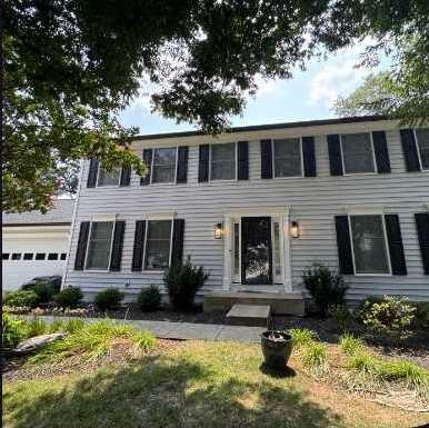 Colonial home after new white Mastic siding, black shutters and gutters by Virginia Exteriors